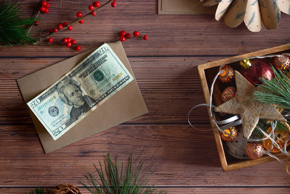 Twenty dollar bill on table with box of ornaments to show to budget for Christmas