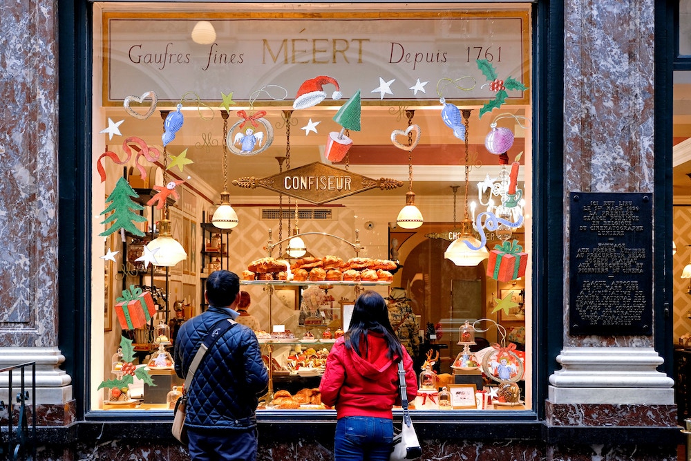 Couple looking in window of bakery decorated for Christmas
