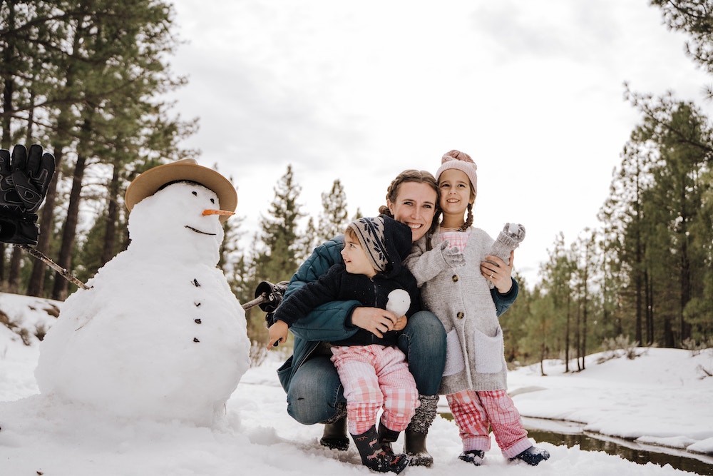 Mom, 2 kids outside with snowman posing for Christmas photo