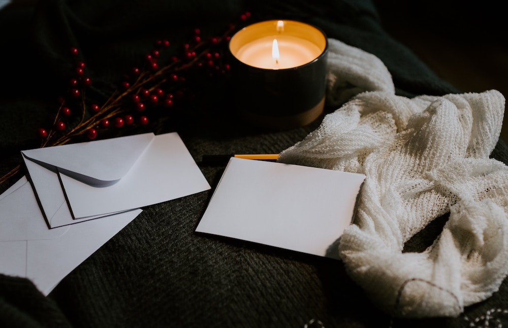 Cards and envelopes on table with a scarf and lit candle