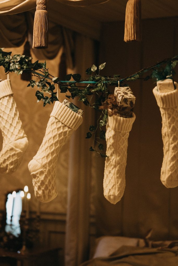 Four white knitted stockings filled with Christmas stocking stuffers