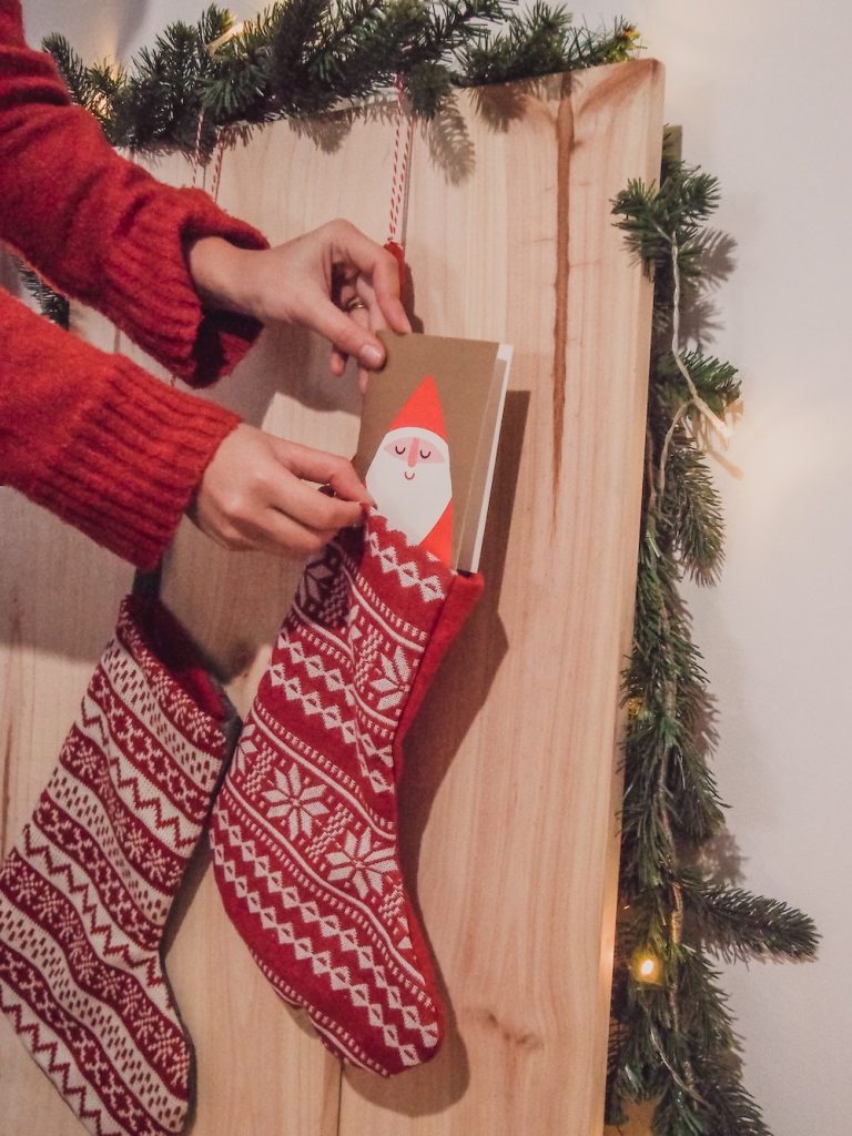 Woman's hand putting Christmas stocking stuffer in stocking.