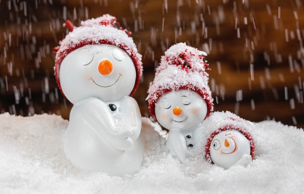 Family of mini snowmen in snow with red hats, represent family fun