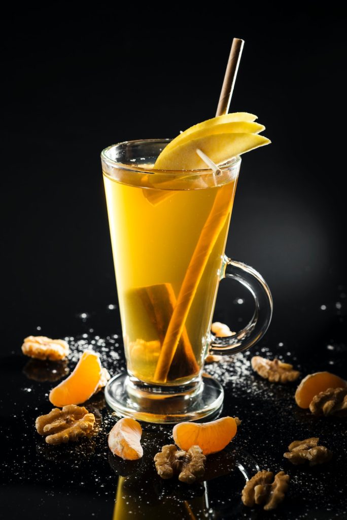 Clear glass with drink, lemon slices and cinnamon sticks.