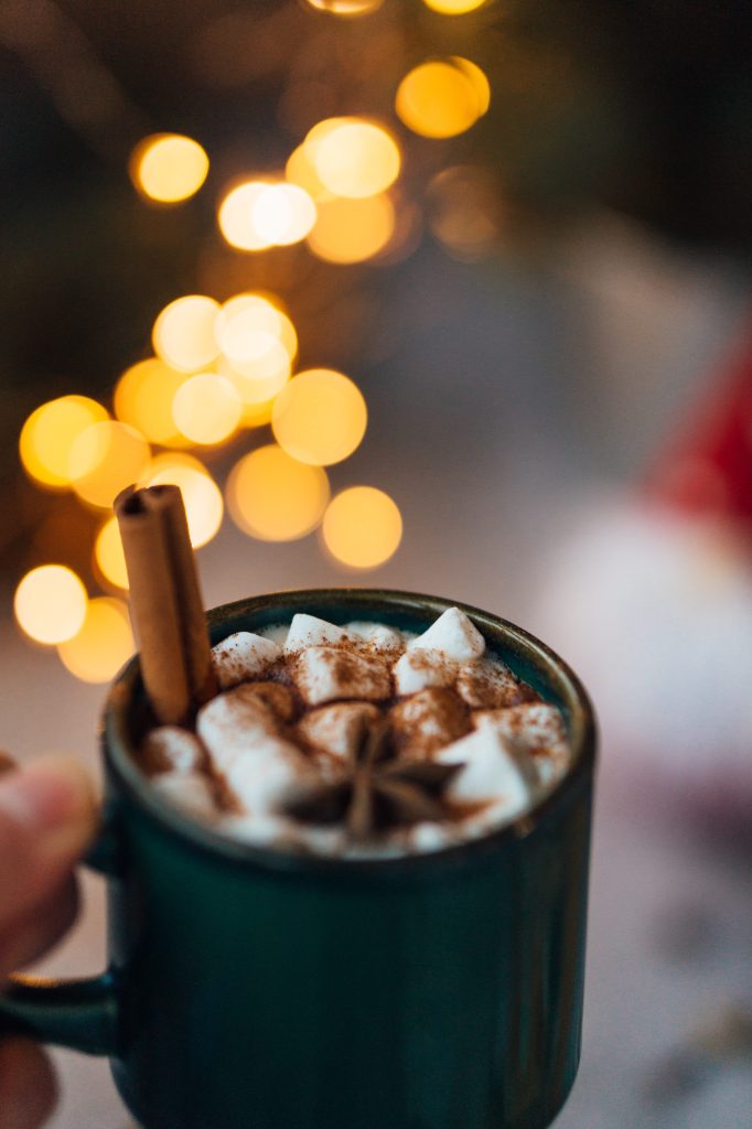 Mug of hot chocolate with cinnamon stick, marshmallows and cinnamon sprinkles.