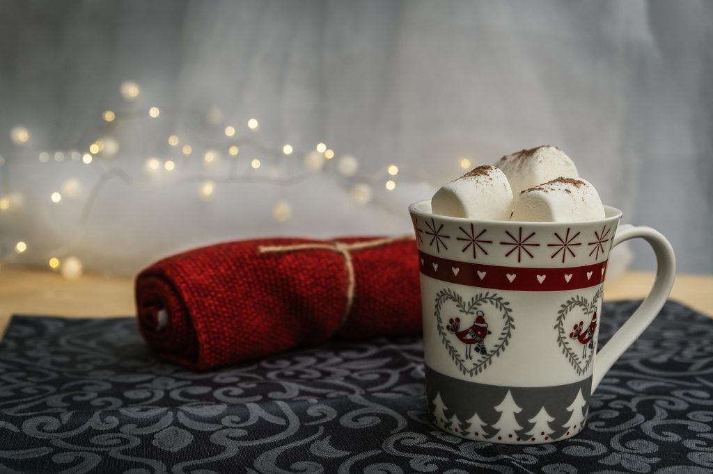 Hot chocolate in mug with marshmallows sitting on gray table with red napkin.