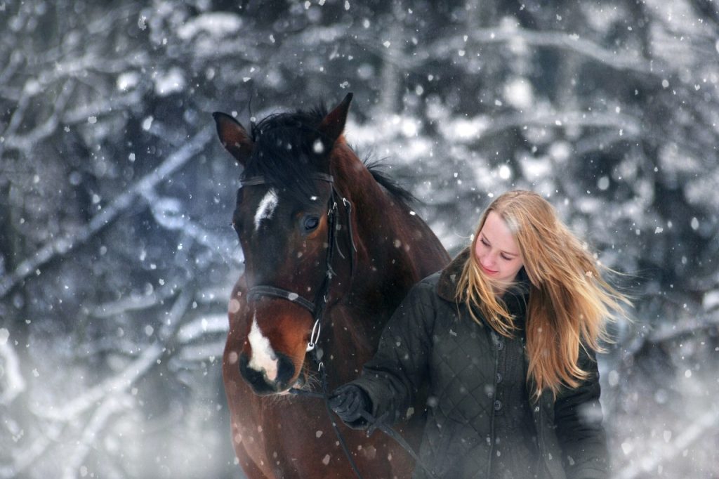Woman walking horse in wintertime to avoid weight gain during holidays