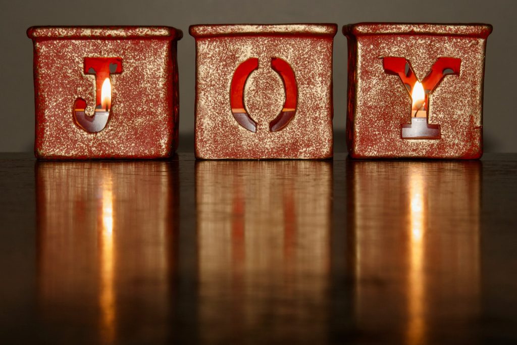 Three candles with the letters JOY on the front symbolizing the joy of the act of gifting collections.