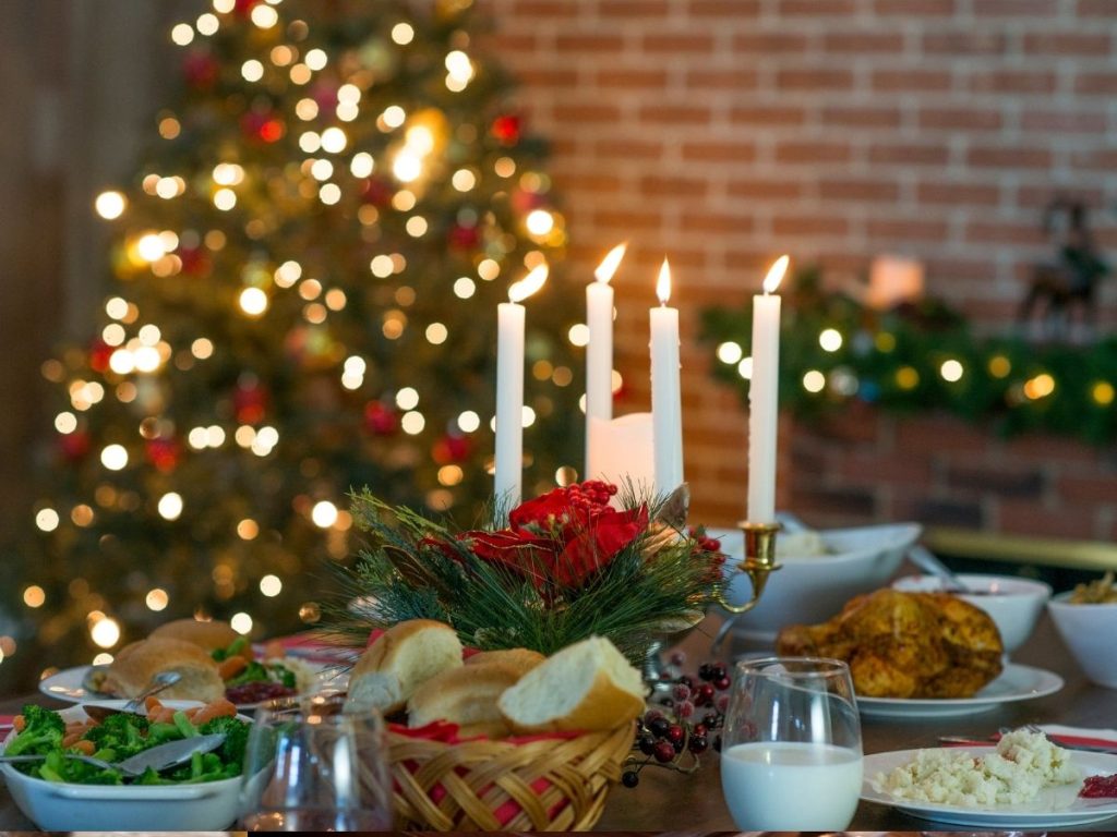 Christmas dinner set on table in front of Christmas tree.