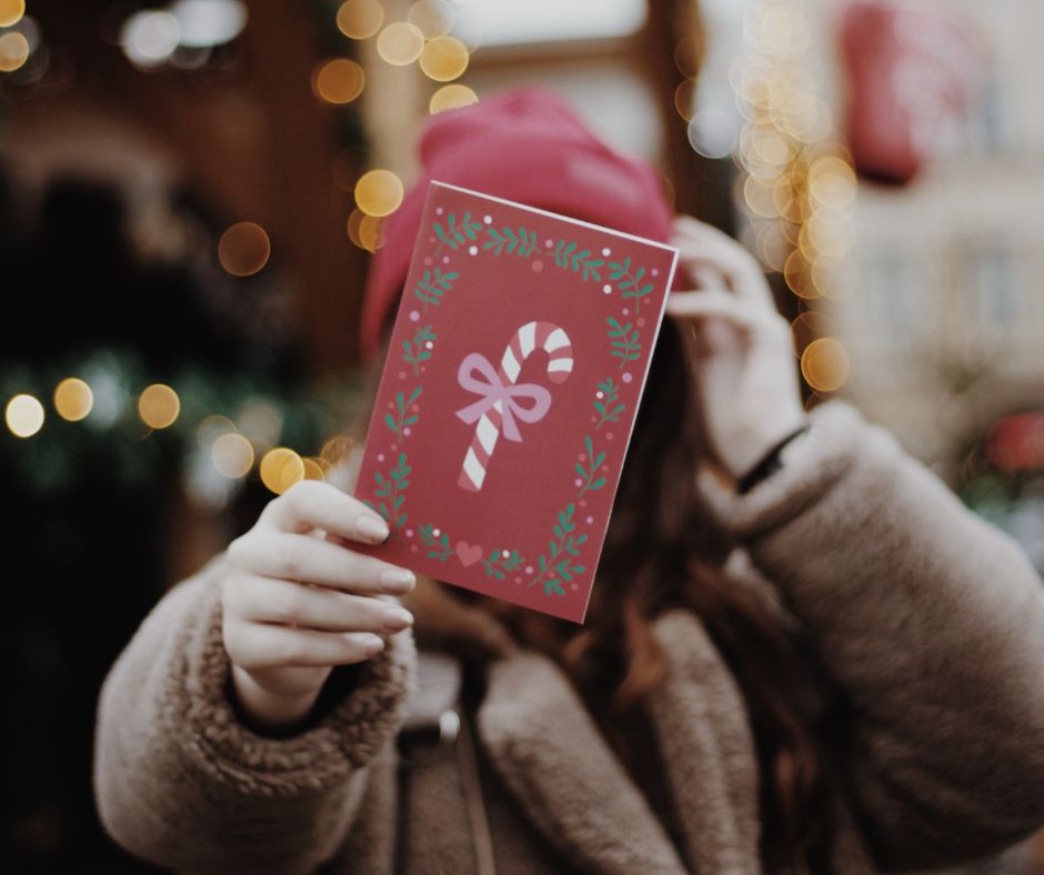 Girl holding Christmas card in front of face.