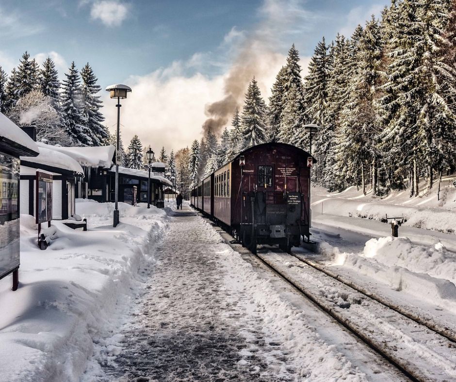 Winter scene with train, trees, snow to depict Christmas savings on travel.