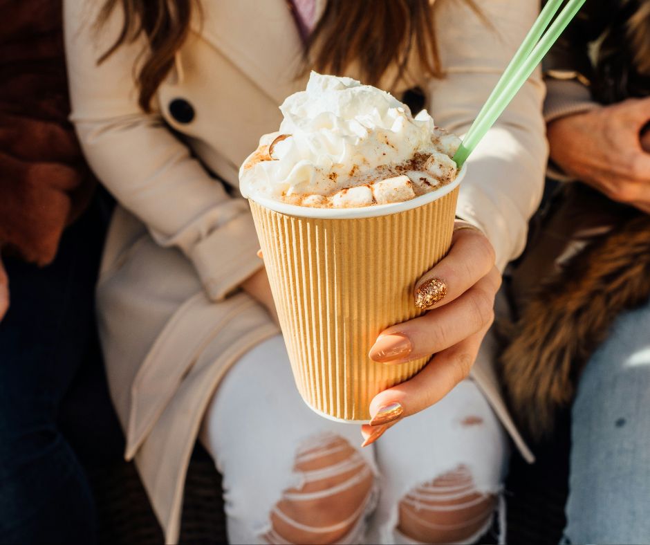 woman holding a gold cup of frozen hot chocolate with green straws