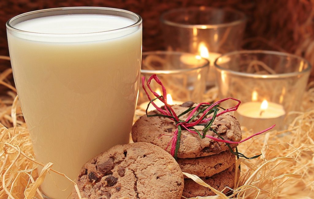 A glass of milk, cookies and candles.