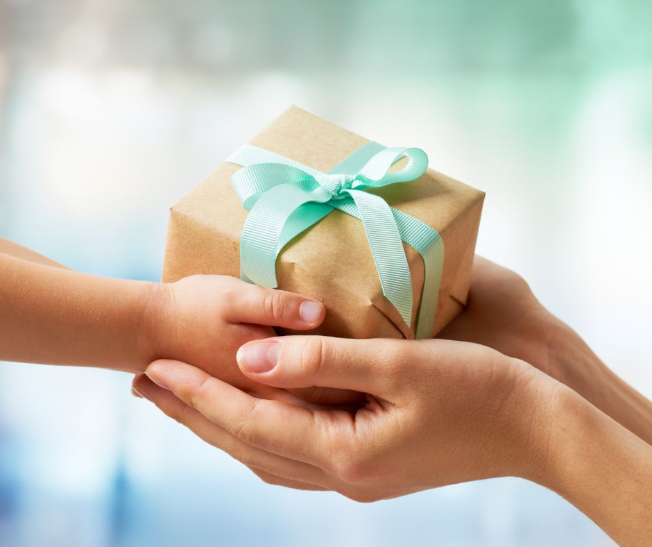 Child giving gift to teacher to show Christmas gift ideas for teachers.