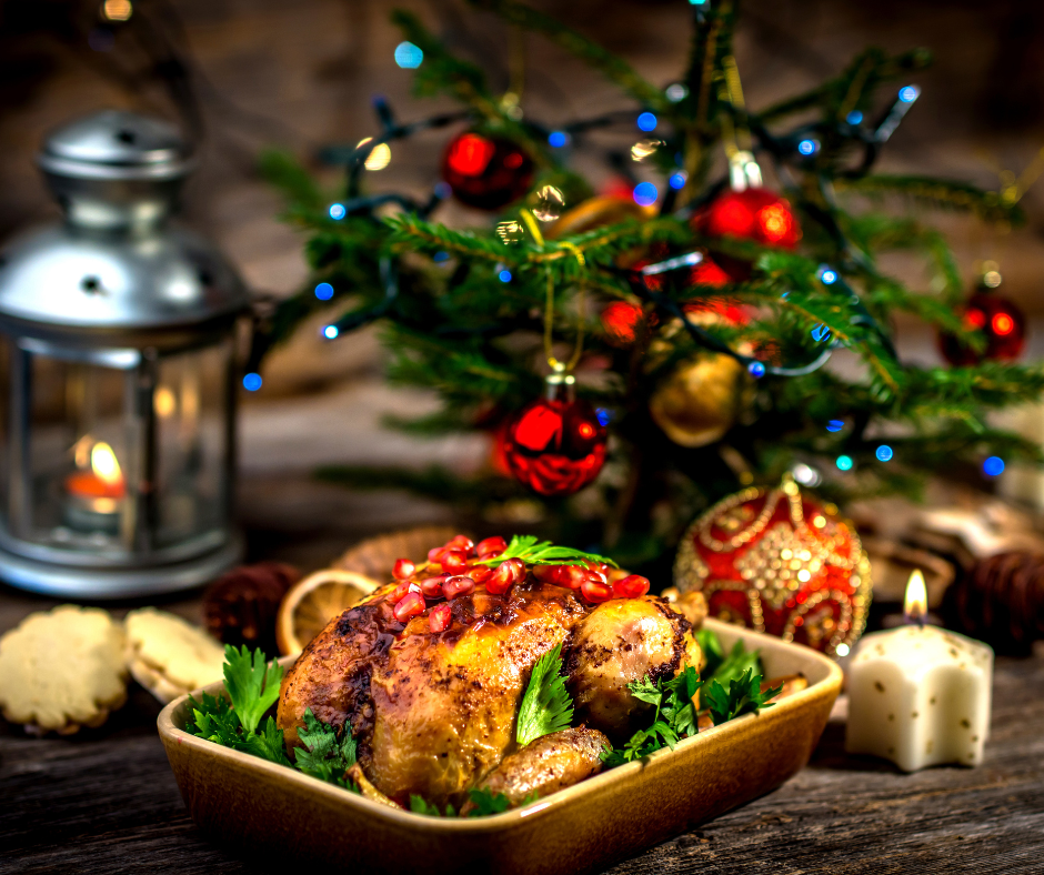 Small roasted turkey in yellow casserole by Christmas tree with candles.