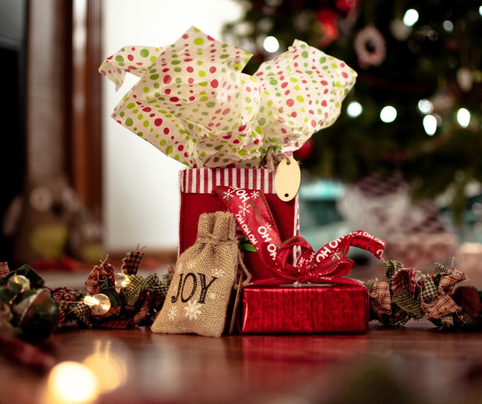 3 different Christmas gifts for couples wrapped in red paper and Joy sack.