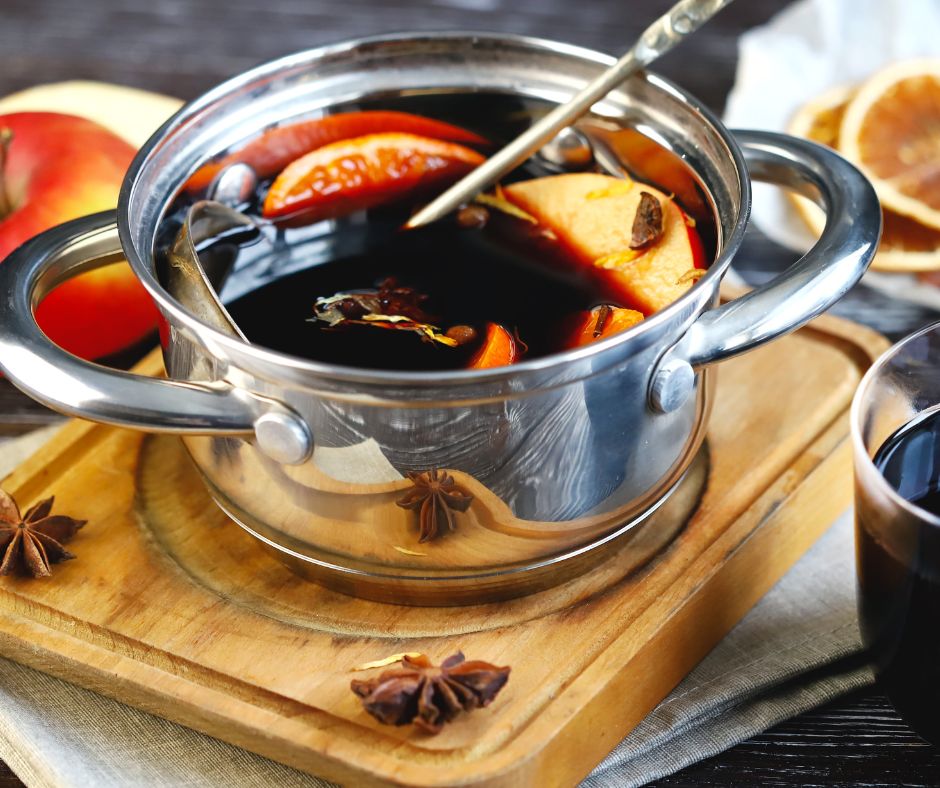 Mulled wine in silver pot sitting on cutting board.