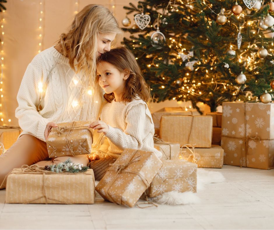 Mother and daughter with Christmas gifts for moms in front of hristmas tree